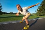 The happy old man rollerblading and thumbs up on the alley